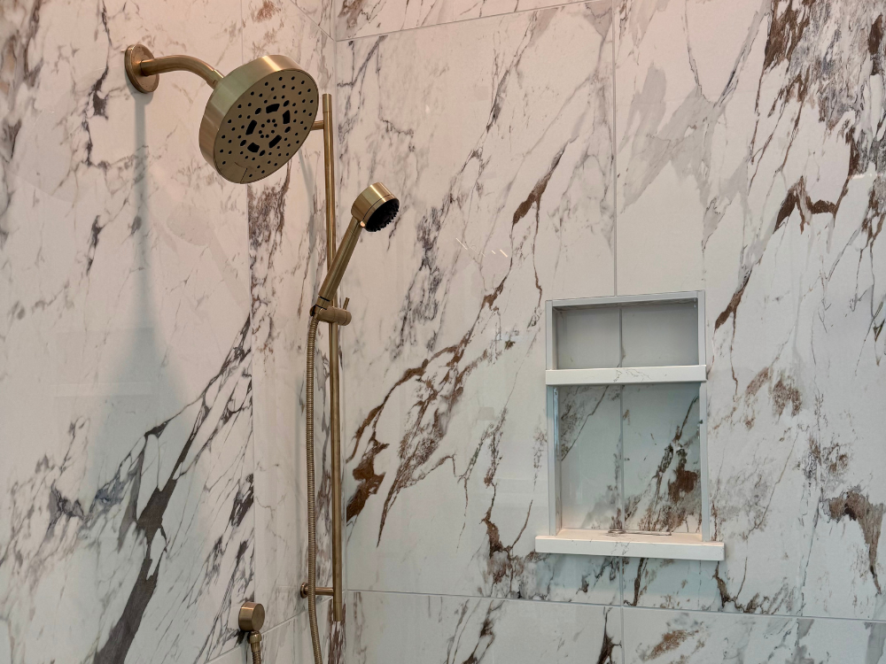 Natural stone tile in a walk-in shower with niche and gold fixtures